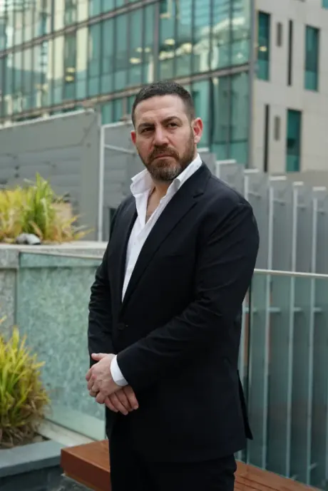 Nader Soussou, founder, in a dark suit, standing outside a glass building